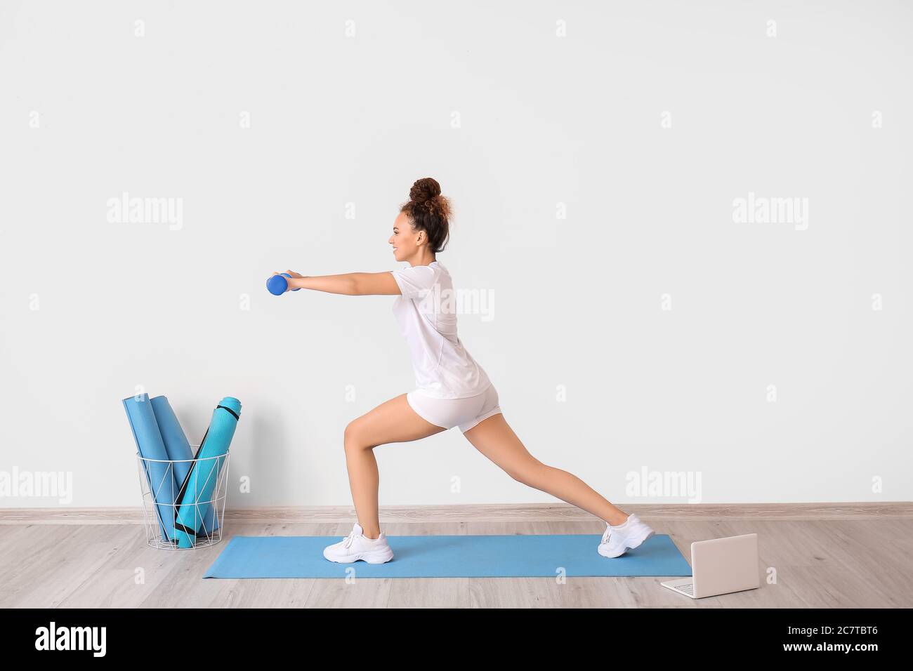 Sporty young woman training against light wall Stock Photo - Alamy