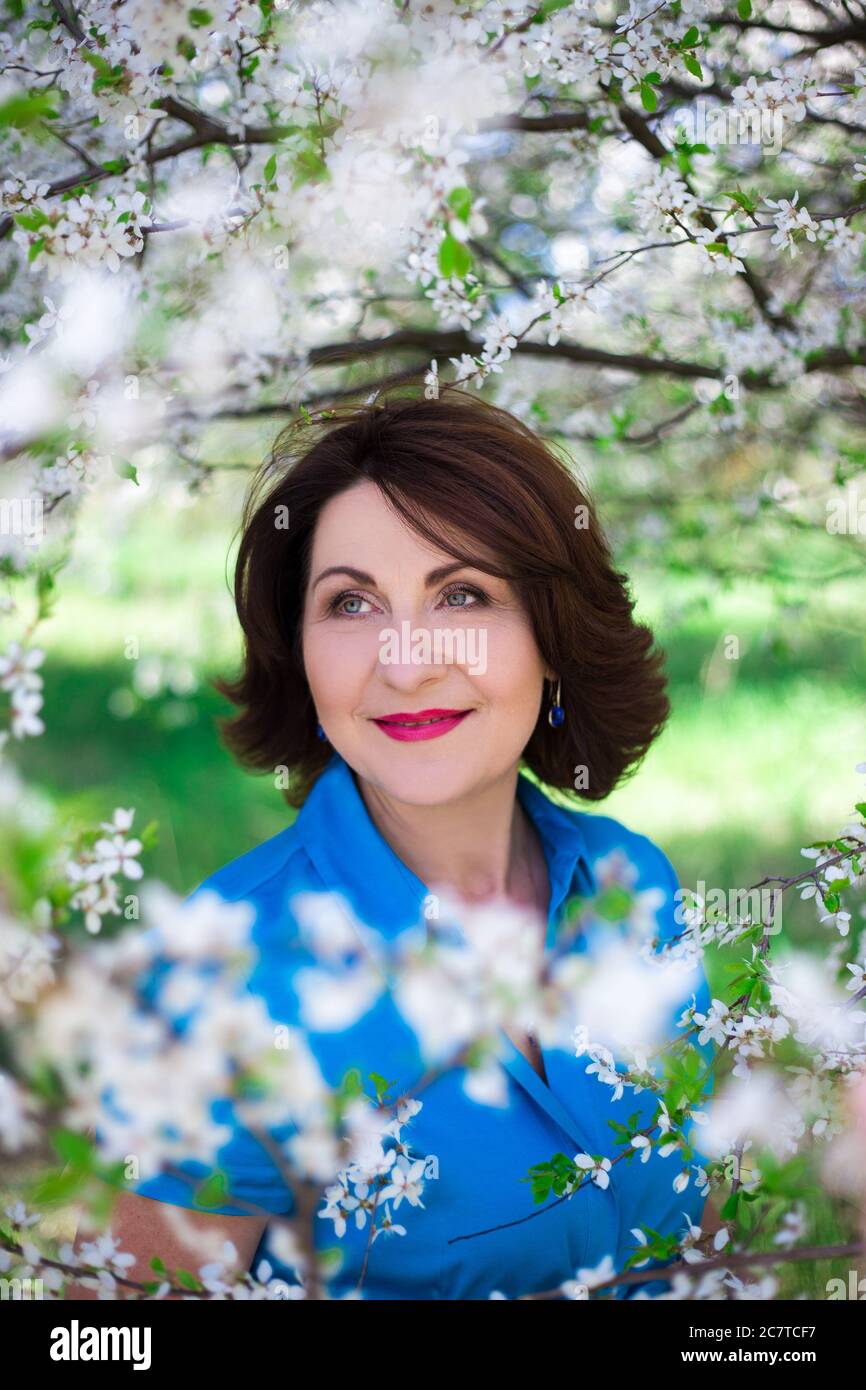 close up portrait of beautiful middle aged woman in blooming garden ...