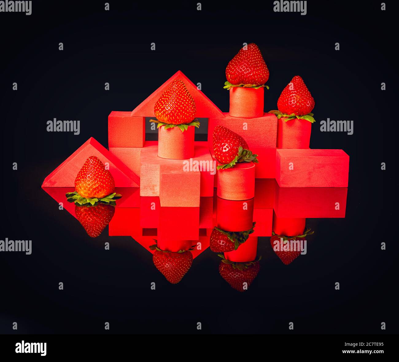 Strawberries on red geometrical structures on black background Stock Photo
