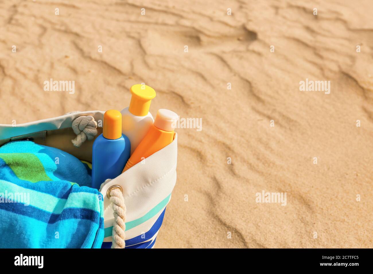 Bag with sunscreen cream on beach Stock Photo
