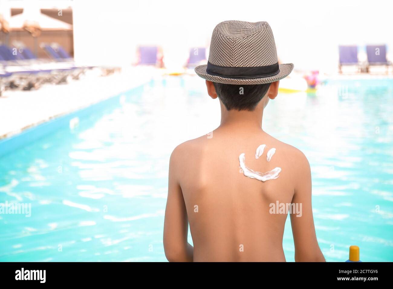 Little boy with sun protection cream on his body near swimming pool Stock Photo