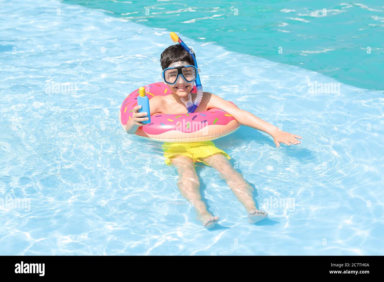 Little boy with sun protection cream and inflatable ring in swimming pool Stock Photo
