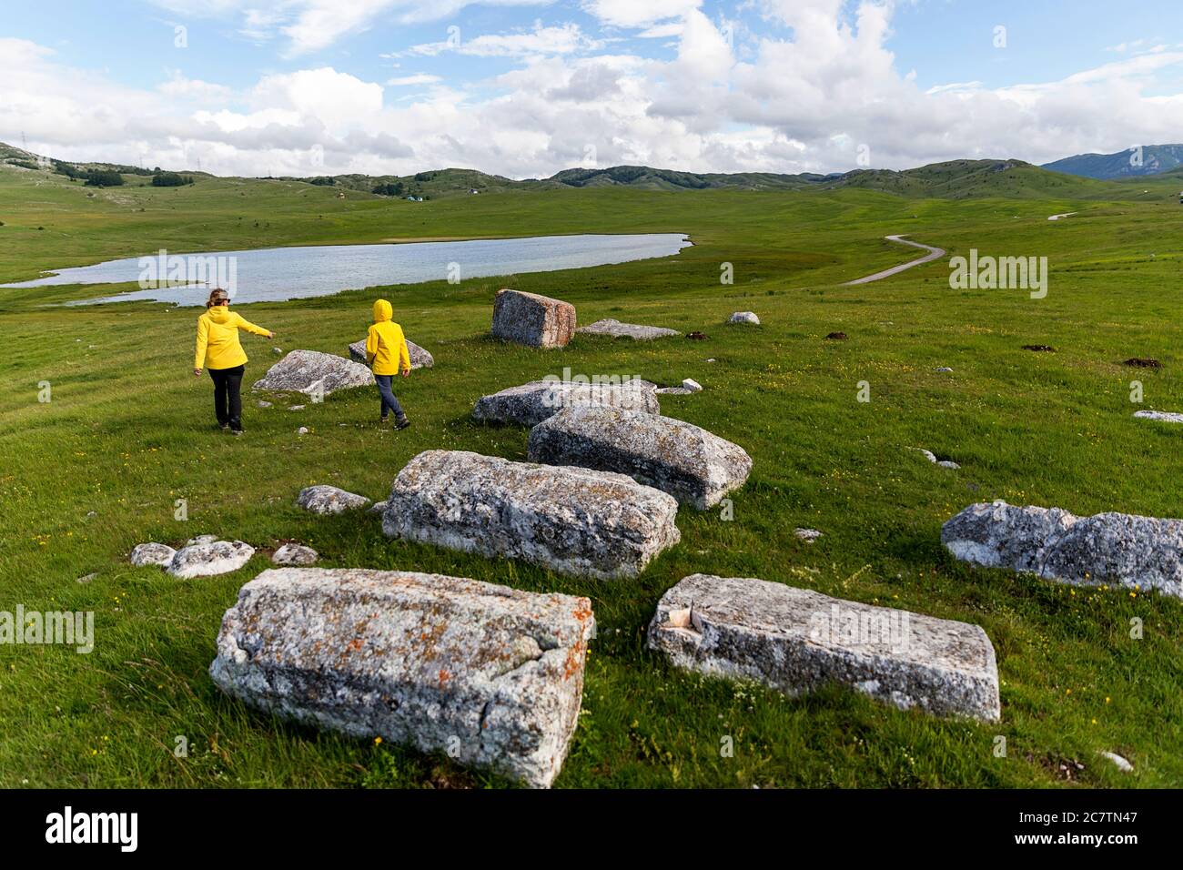 Mother and son walking among gravestones Stecci, Necropolis of the Bogumiles, near Zabljak, Zabljak Province, Montenegro Stock Photo