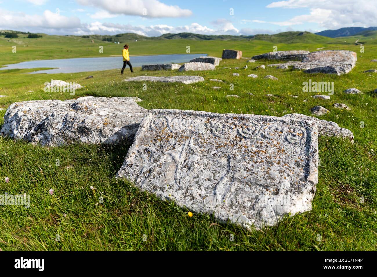 Woman at gravestones Stecci, ancient burial site near Riblje lake, near Zabljak, Zabljak Province, Montenegro Stock Photo