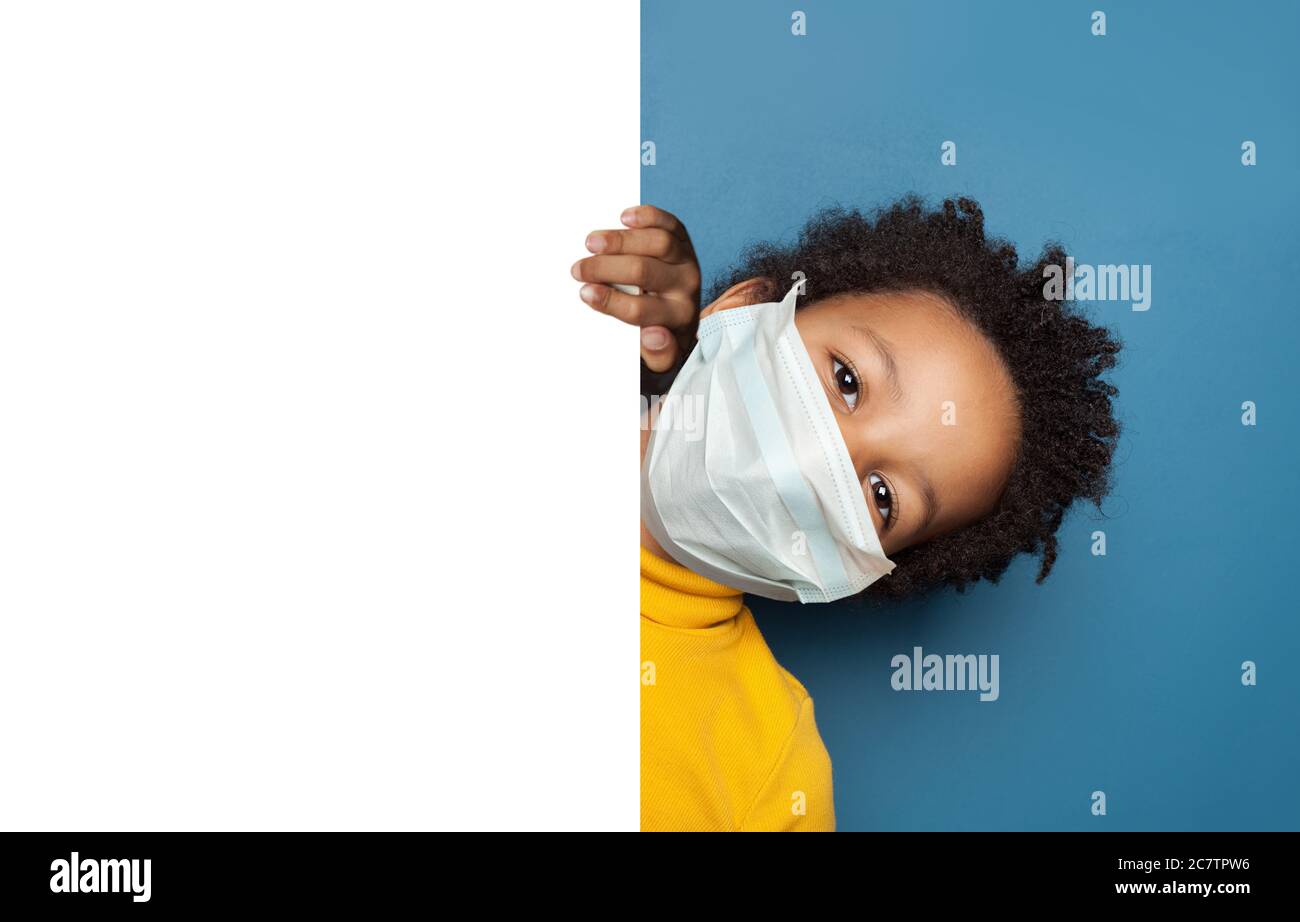 Black child boy in medical protective face mask holding white empty ...
