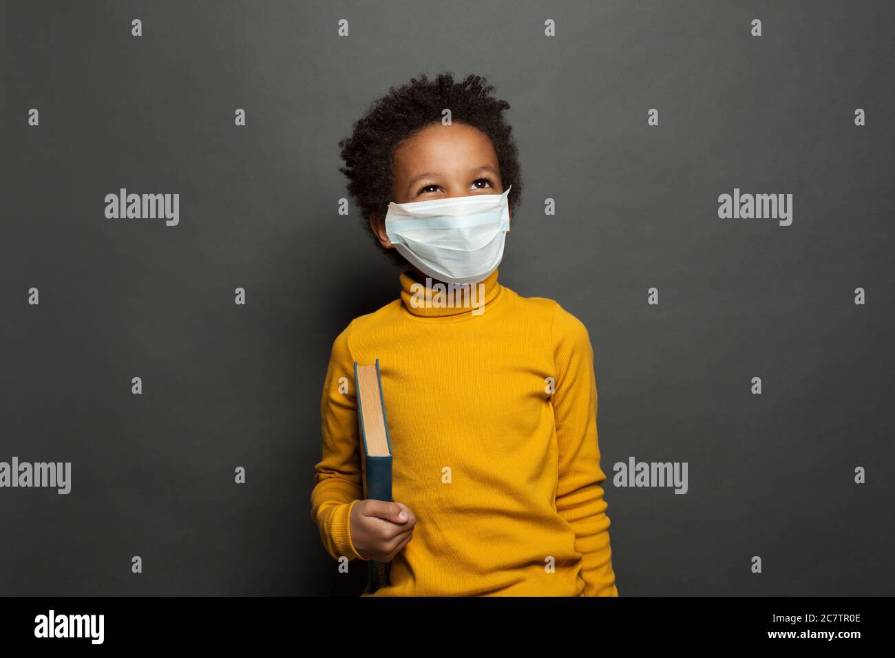 Happy black child boy in medical protective face mask on blackboard ...