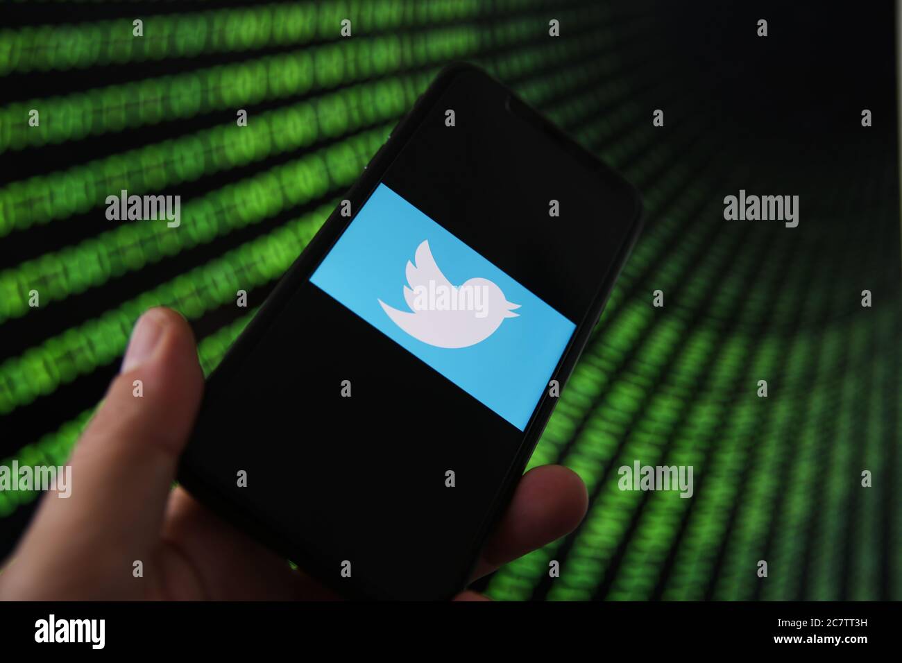 Viersen, Germany - July 9. 2020: View on mobile phone with twitter logo hold by hand. Screen with tunnel of binary code numbers background.(selective Stock Photo