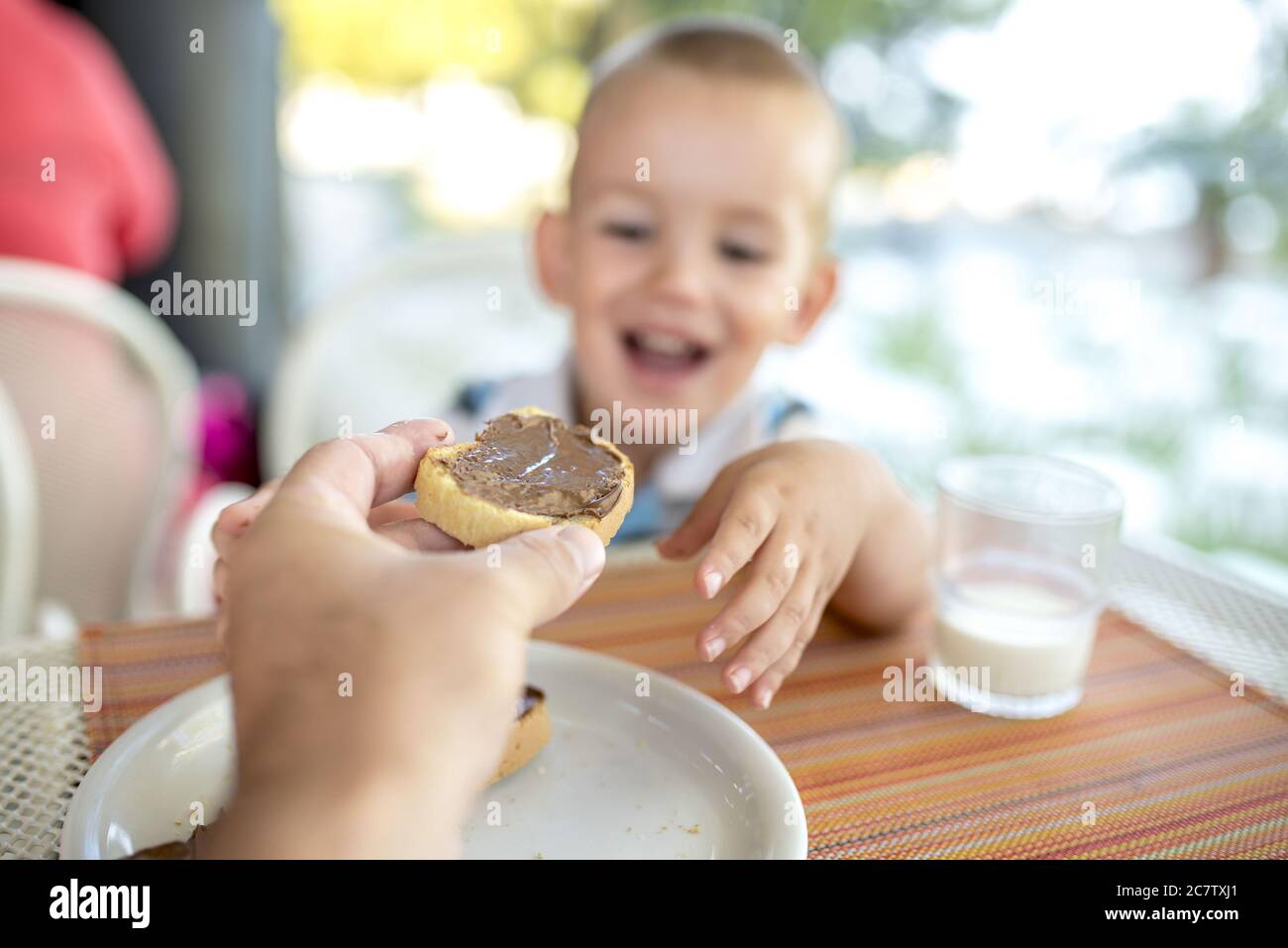 Happy Caucasian child eating bread with chocolate for breakfast Stock Photo