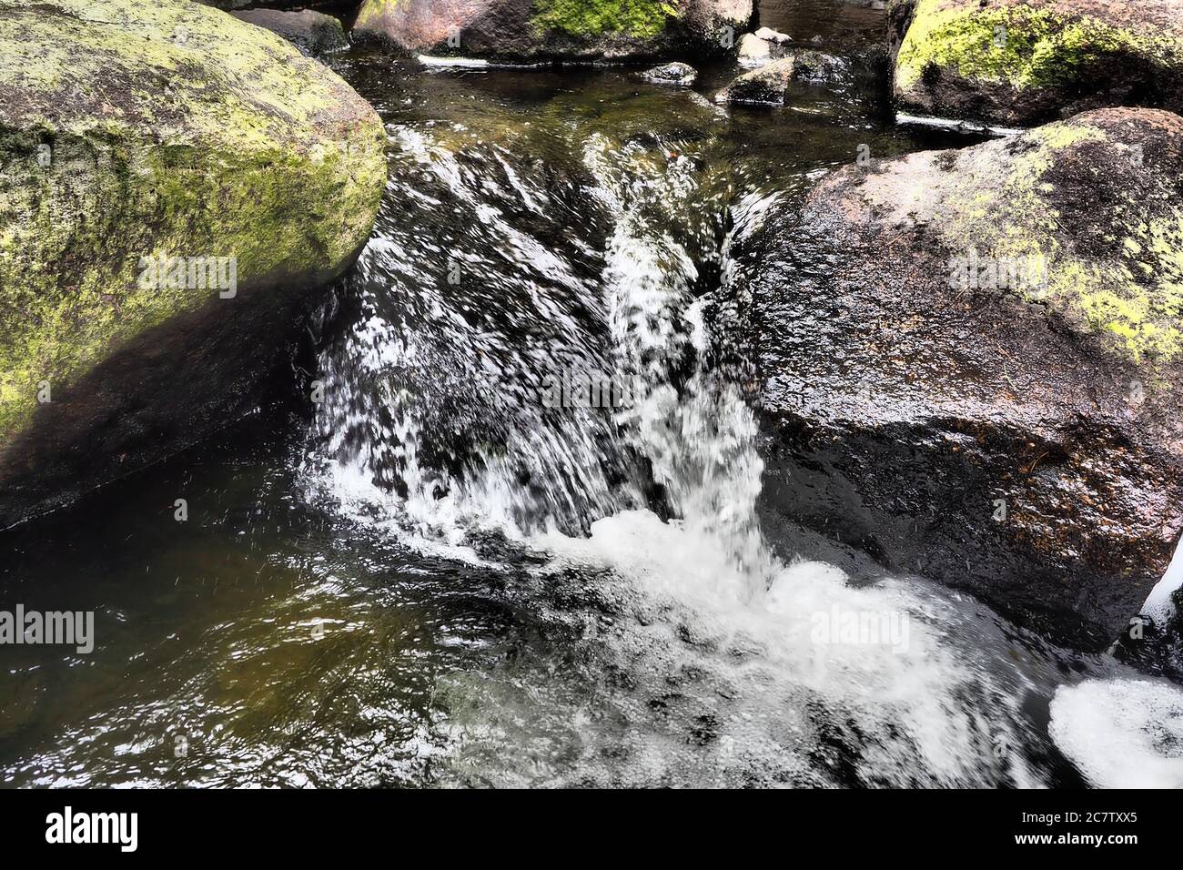 Closeup of a river flowing between two big rocks Stock Photo - Alamy