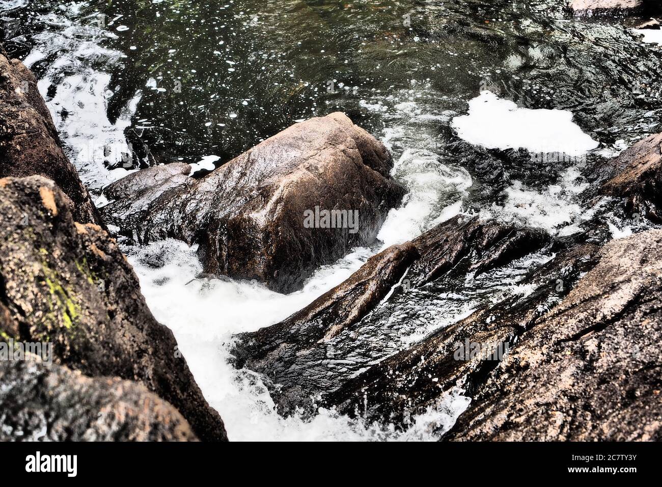 Close-up shot of a river collapsing with rocky landscape and flowing ...