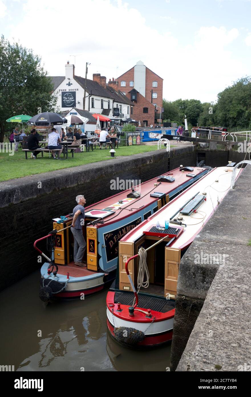 Narrowboats at Warwick Top Lock with people outside The Cape of Good Hope Pub during the easing of Covid-19 lockdown, Warwick, UK. 19th July 2020. Stock Photo