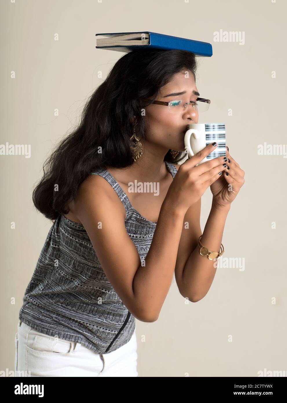 Beautiful young girl with book and cup of tea or coffee posing on a ...