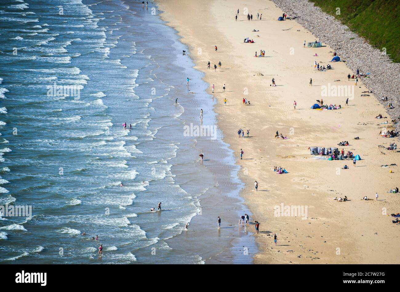 Rhossili, Gower, Wales, UK. 19th July 2020. UK Weather : People are dotted along the coastline and the tides comes in at Rhossili in Gower, south Wales on the first weekend of the Summer Holidays as visitors enjoy the more relaxed lockdown rules and good weather. Robert Melen/Alamy Live News Stock Photo