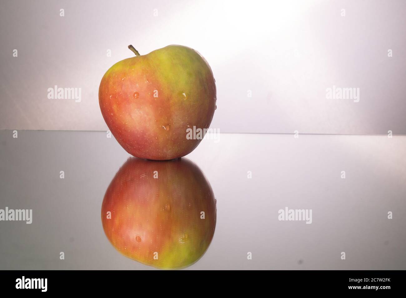 Red apple on mirroring table. Gorizontal image with copy space. Stock Photo