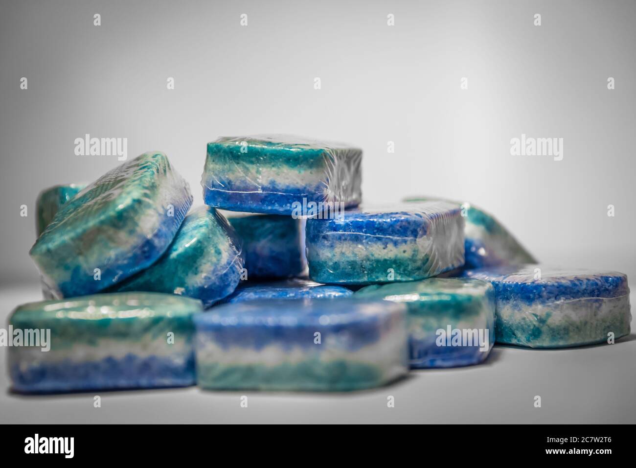 Bunch of dishwasher tablets, randomly stacked, blue, white and green colored on a white background Stock Photo
