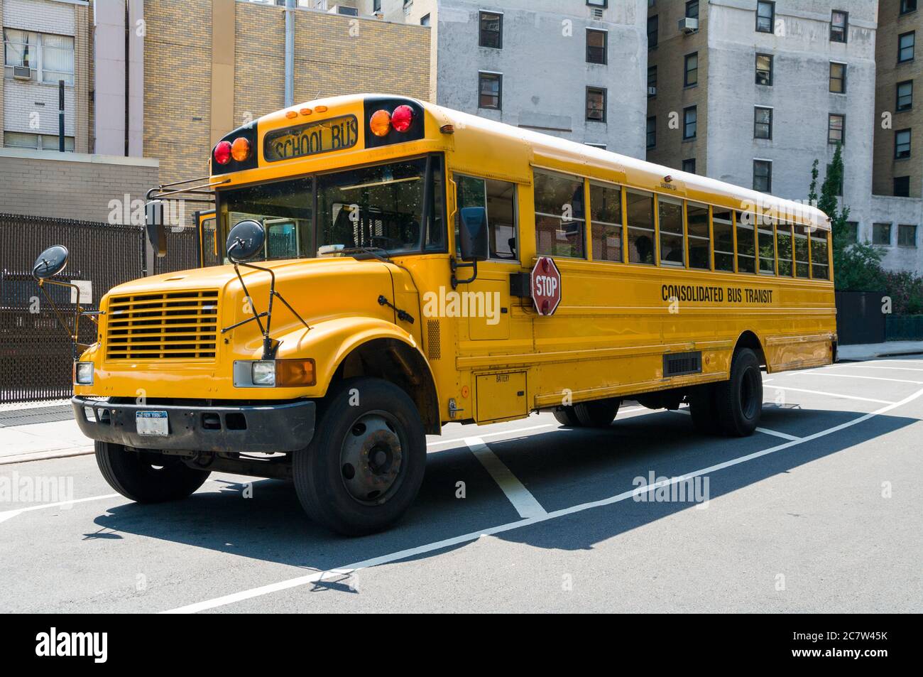 Isolated yellow typical USA american public school bus parked on street in city, New York Stock Photo
