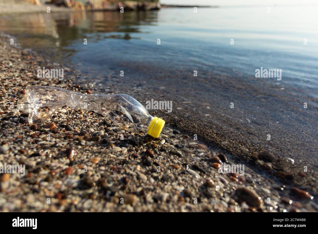 Plastic Bottle Lying On Beach Near Water Outdoors, Ecology Background Stock Photo