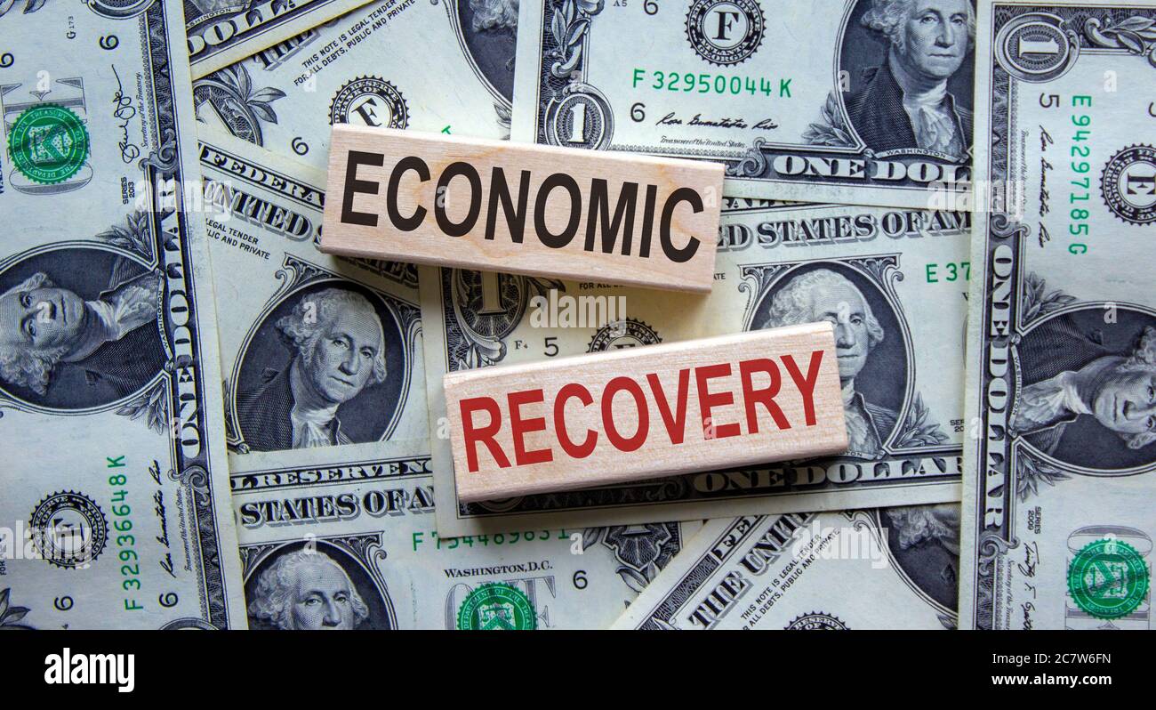 Concept words 'economic recovery' on wooden blocks on a beautiful background from dollar bills. Stock Photo