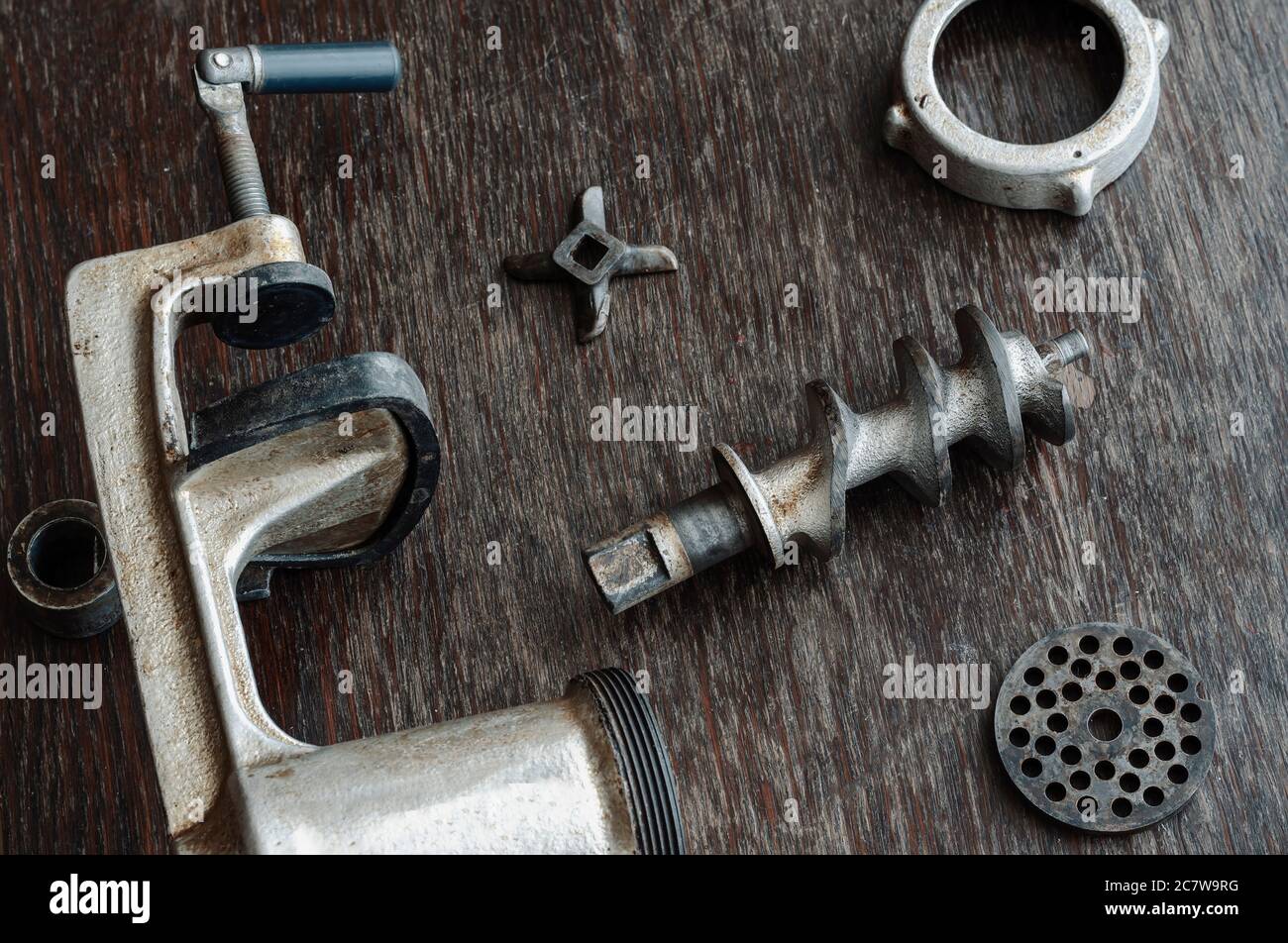 https://c8.alamy.com/comp/2C7W9RG/disassembled-manual-vintage-meat-grinder-on-wooden-table-cast-iron-body-of-meat-grinder-auger-grate-special-knife-and-nut-shooting-from-above-at-2C7W9RG.jpg