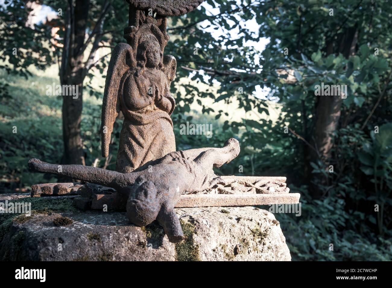 Lying Jesus Christ and a praying angel. Broken metal sculpture on a