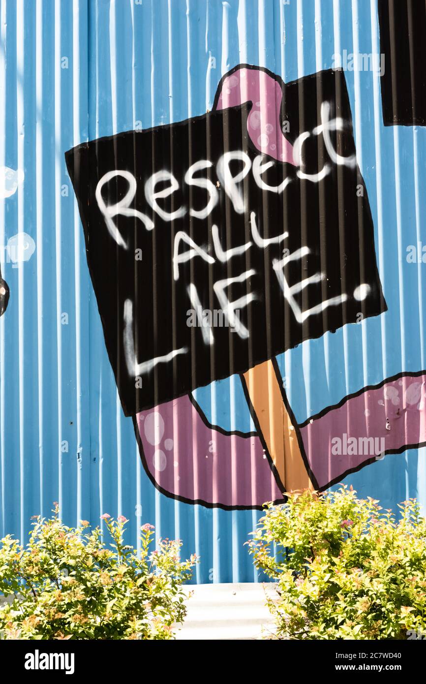And artistic rendition of an octopus arm holding a black sign with white letters that says respect all life on a colorful corrugated blue background. Stock Photo