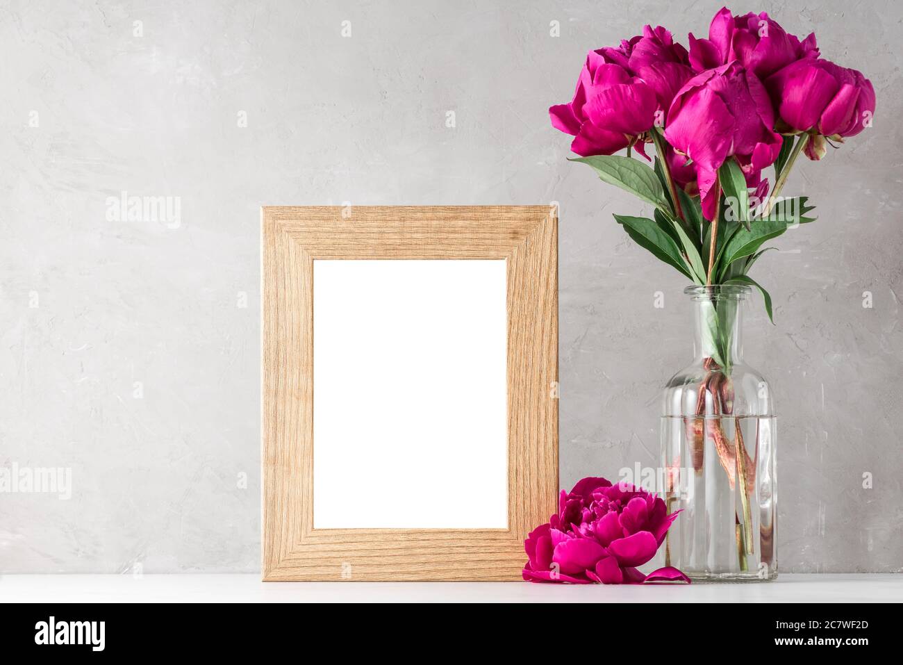 red peony flowers bouquet with blank photo frame on white background. mock up. still life. wedding or holiday concept. festive background Stock Photo