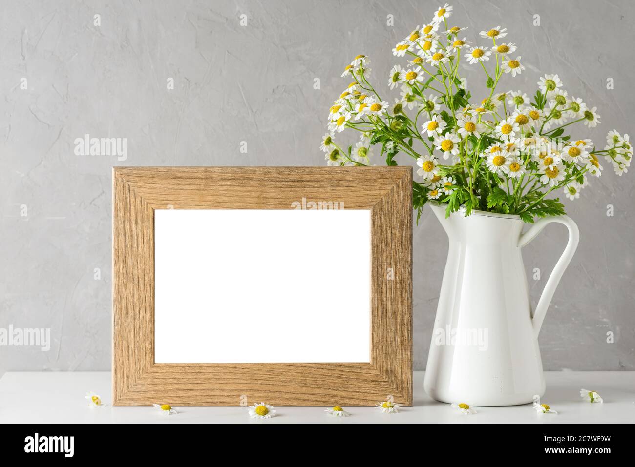 White chamomile flowers bouquet with blank photo frame on white background. mock up. still life. wedding or holiday concept. festive background Stock Photo