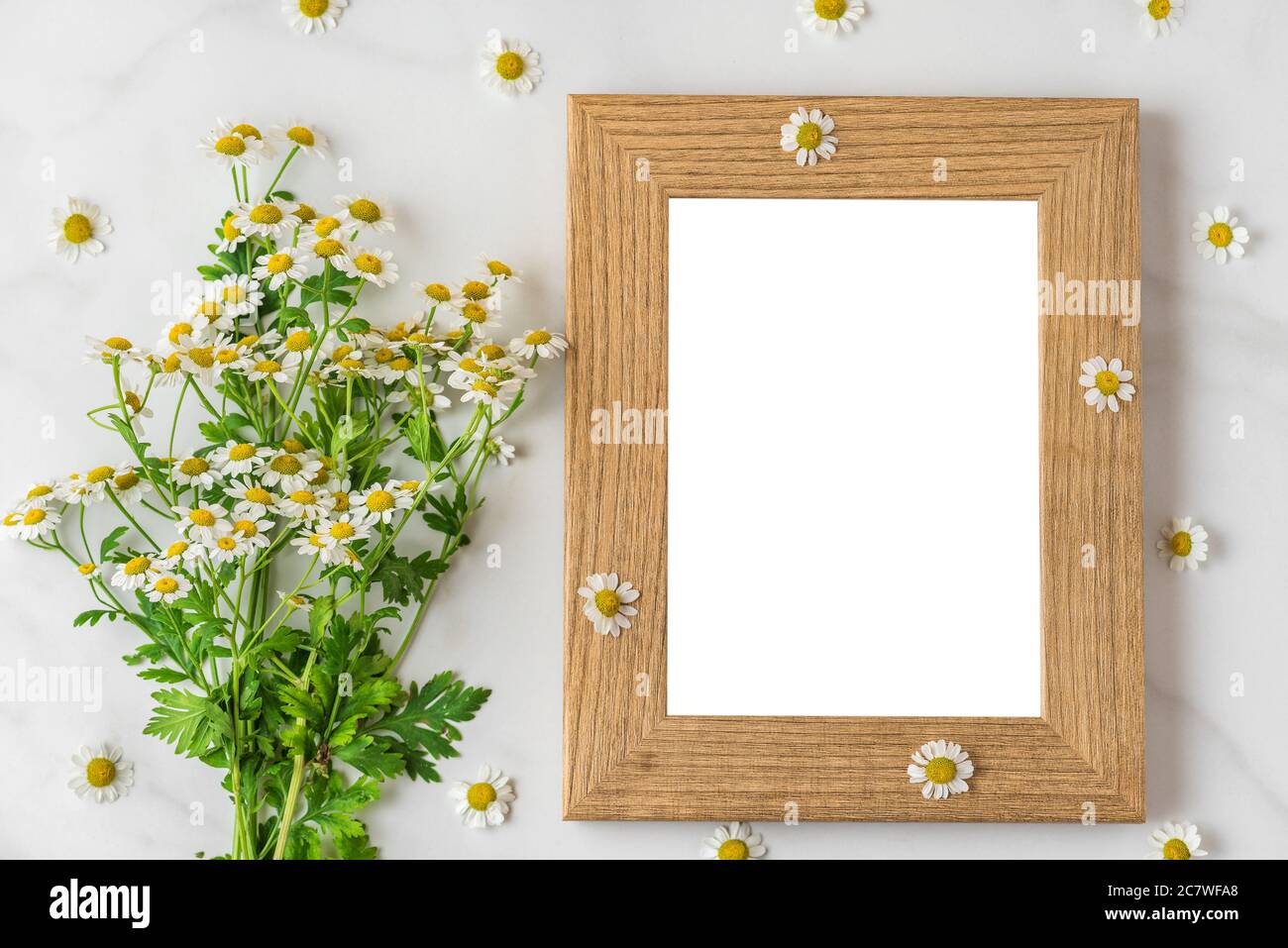 White chamomile flowers bouquet with blank photo frame on white background. mock up. flat lay. top view. wedding or holiday concept. festive backgroun Stock Photo