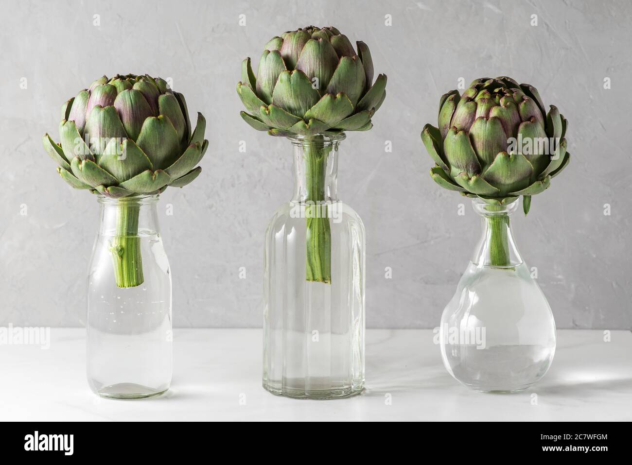 Artichoke vegetables in the bottles on white background. Creative modern food still life. Minimal concept Stock Photo