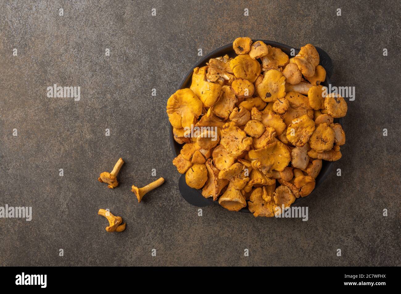 Raw fresh chanterelle fox mushrooms in a cast-iron frying pan on a wooden background. Top view, copy space for text  Stock Photo