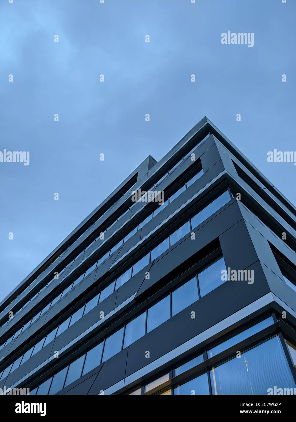 Vertical low angle shot of a glass modern building under a blue sky ...