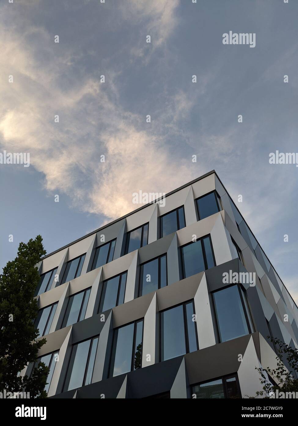 Vertical low angle shot of a glass modern building under a blue sky ...