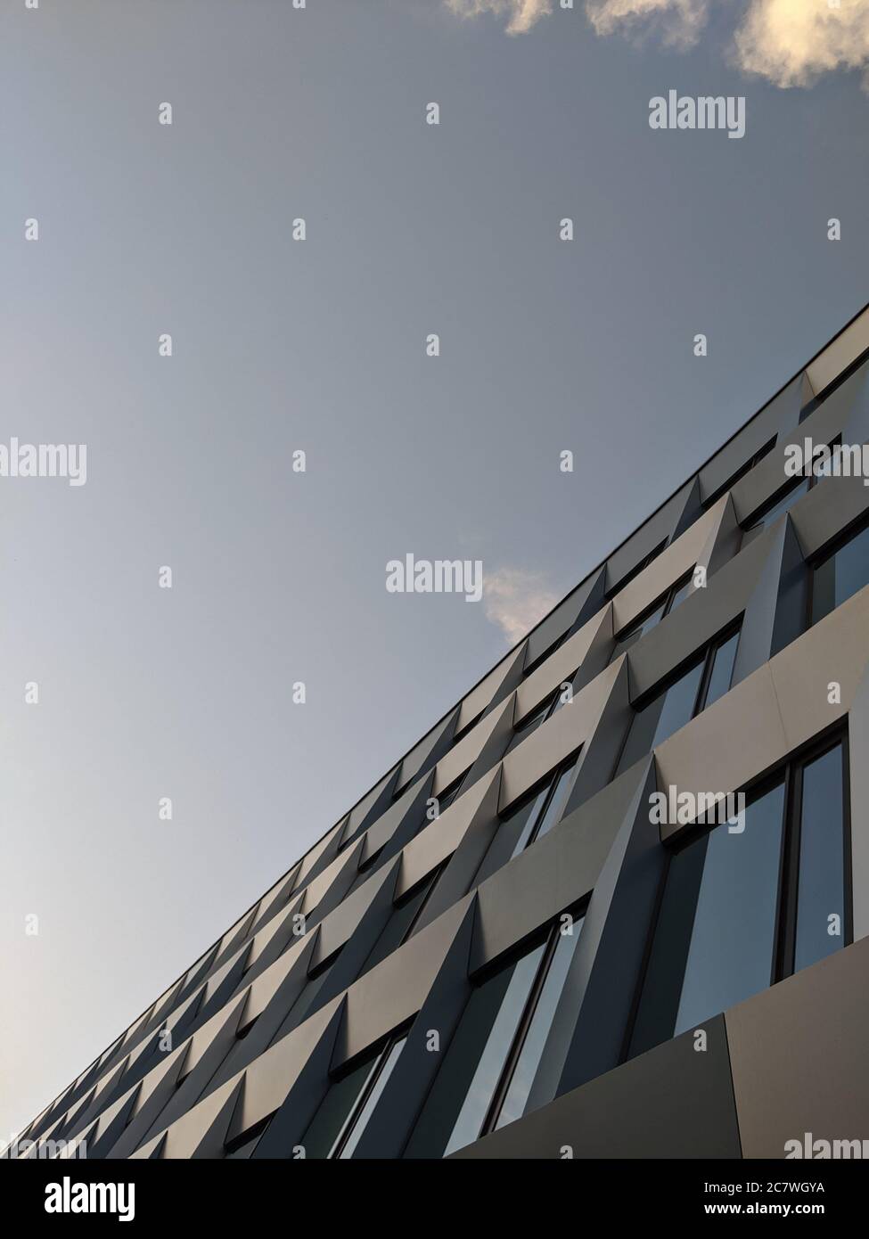 Vertical low angle shot of a glass modern building under a blue sky ...