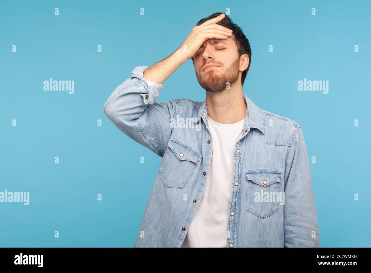 I forgot, my fault. Portrait of upset man in worker denim shirt standing with facepalm gesture, blaming himself, feeling sorrow regret because of bad Stock Photo