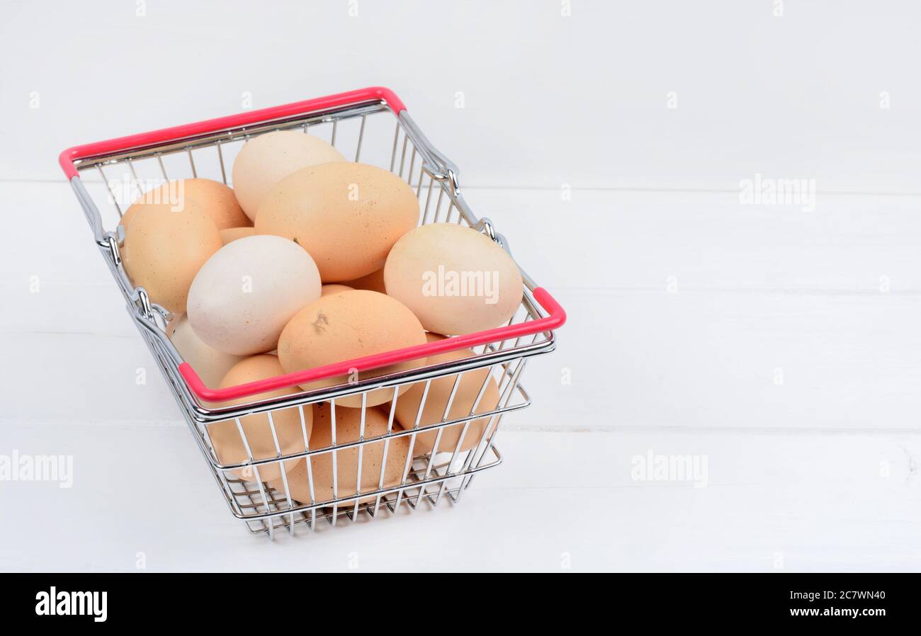 Stack of eggs in a shopping cart on a white wood table Stock Photo
