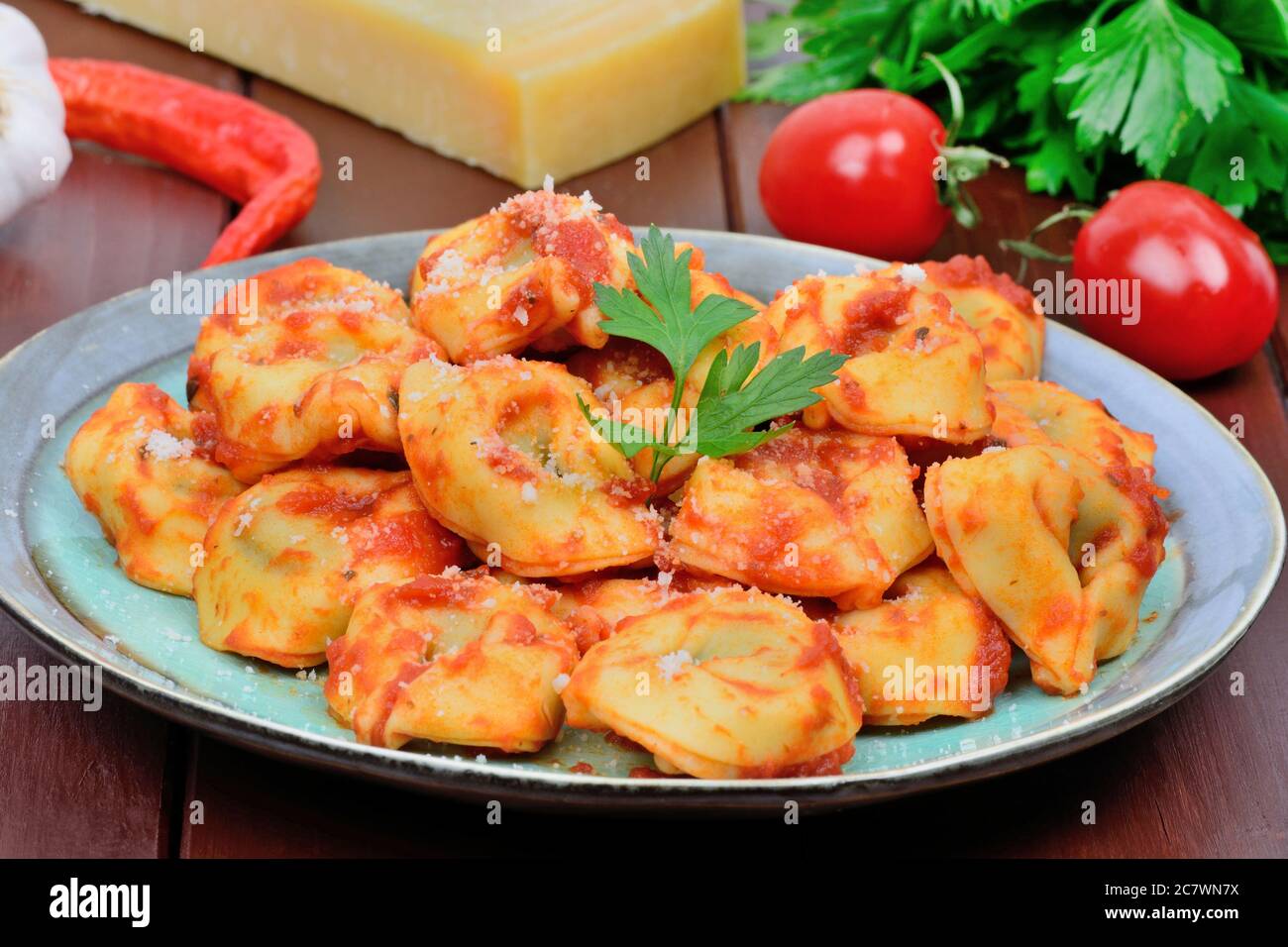 Tortellini with tomatoes sauce in a plate on a wood table Stock Photo