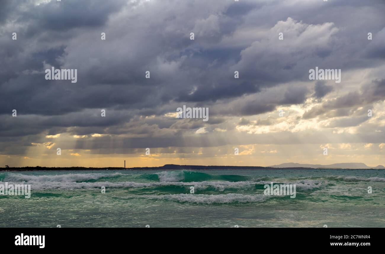 Stormy dark clouds above the sea with sandy beach and curling waves ...