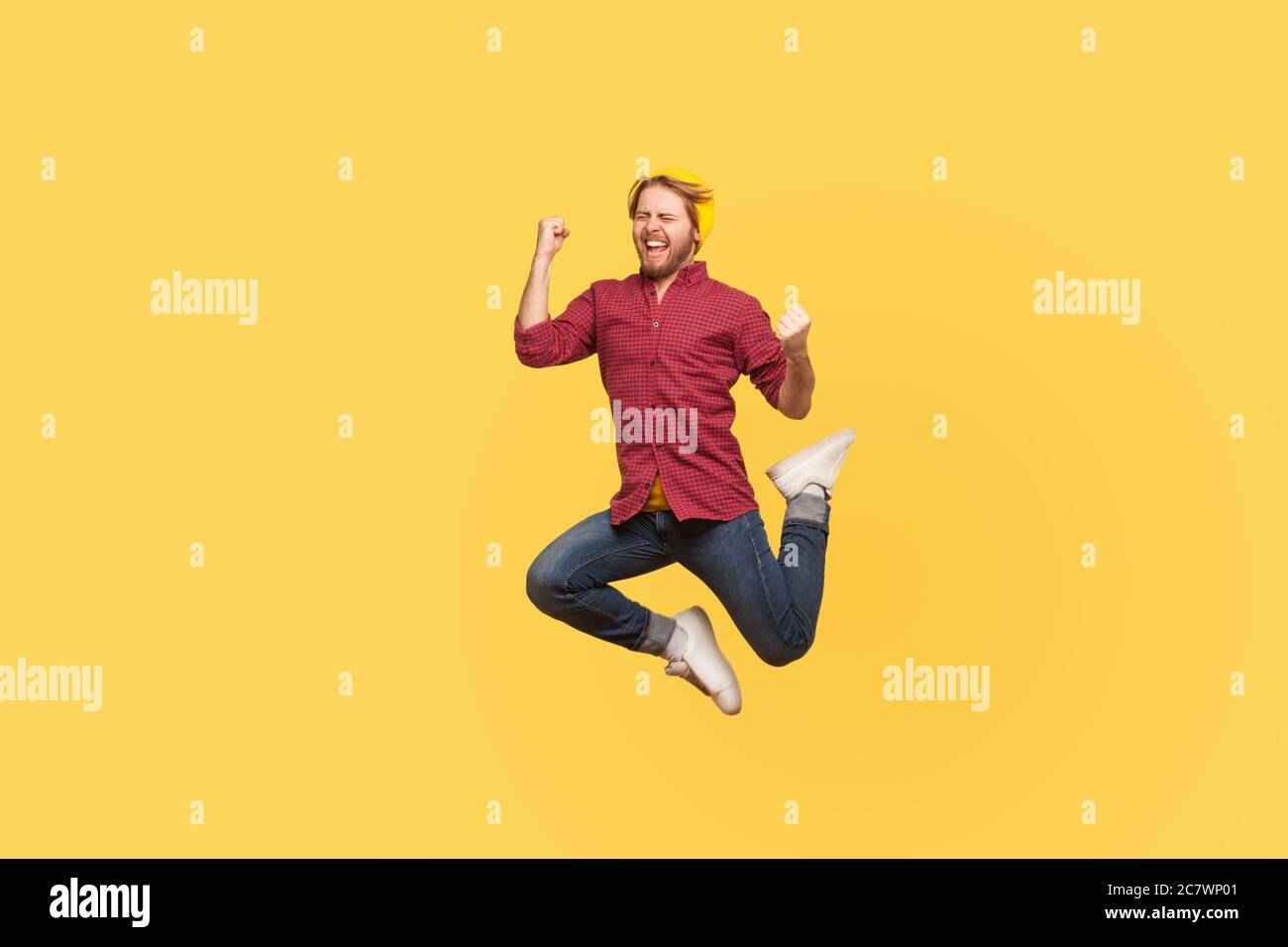 Enthusiastic delighted victorious guy jumping high trampoline, flying in air shouting for joy, crazy about success, triumphal winning. Life people ene Stock Photo