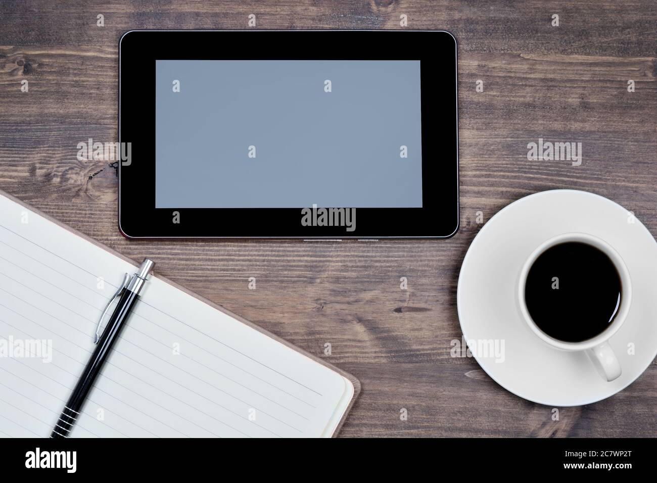 Empty digital tablet pc with notebook and coffee on a wood table Stock Photo