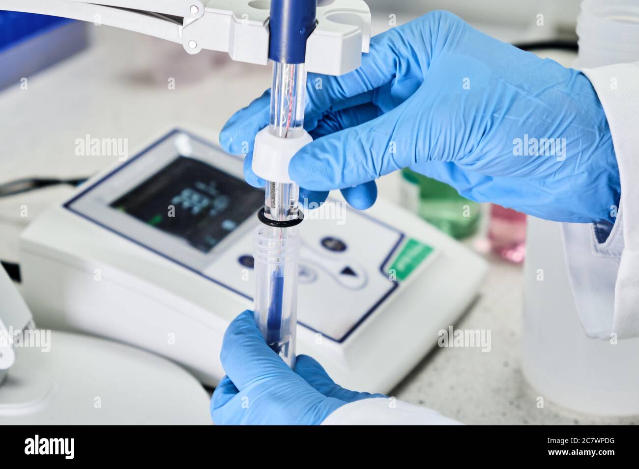 Woman in a rubber gloves holding a glass electrode for measuring of pH