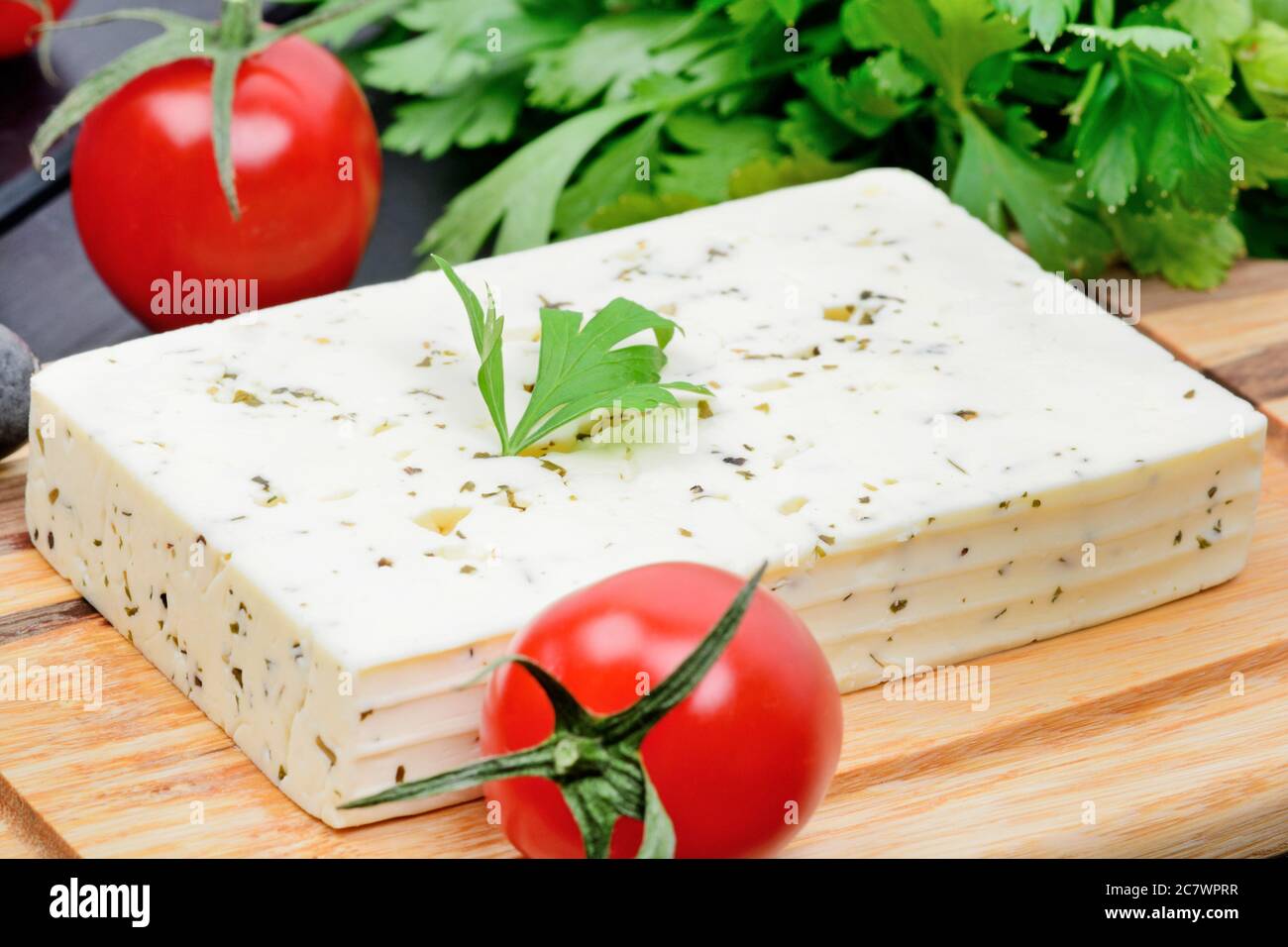 Close up of cheese with herbs and vegetables on wooden table Stock Photo