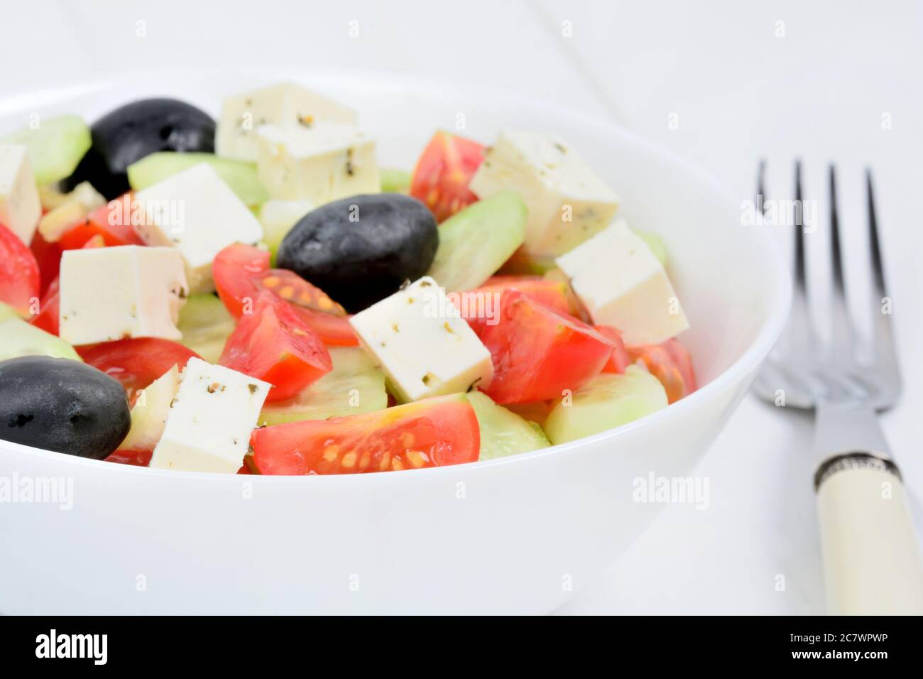 Vegetables salad with cheese in a bowl on white  wooden table Stock Photo