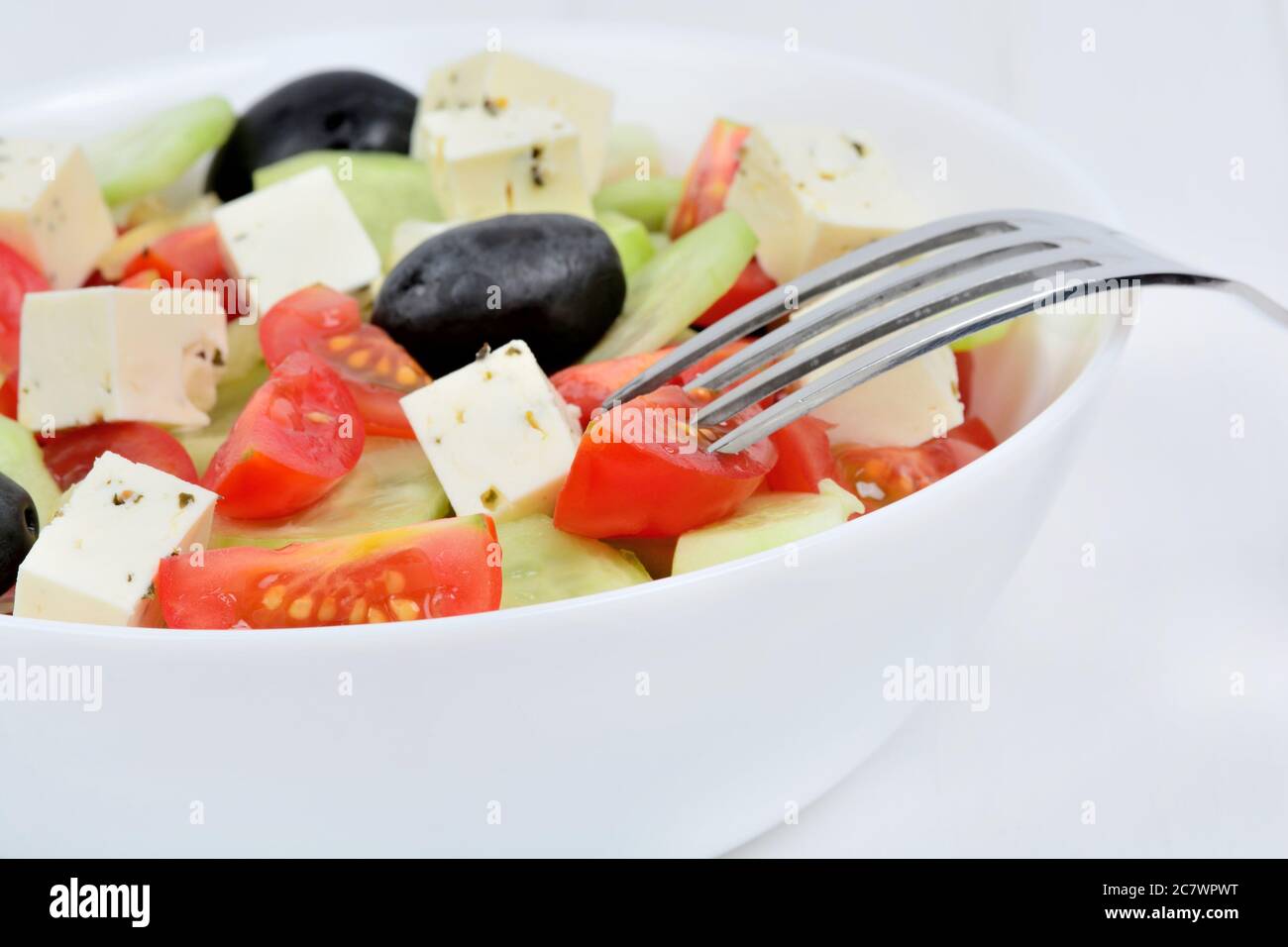Delicious vegetables salad with cheese in a bowl on white wooden table Stock Photo
