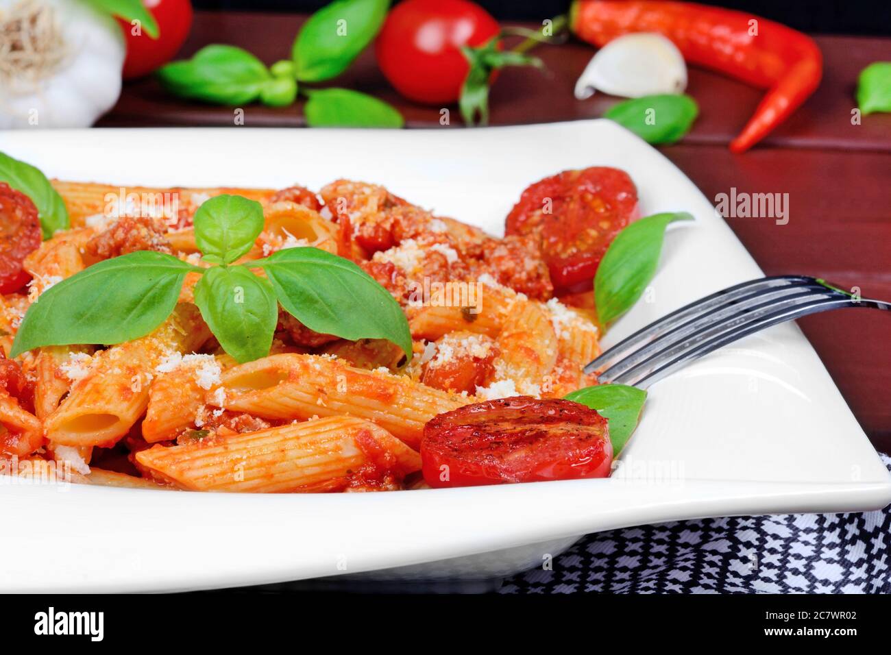 Penne with tomatoes sauce and parmesan in a plate on a wood table Stock Photo