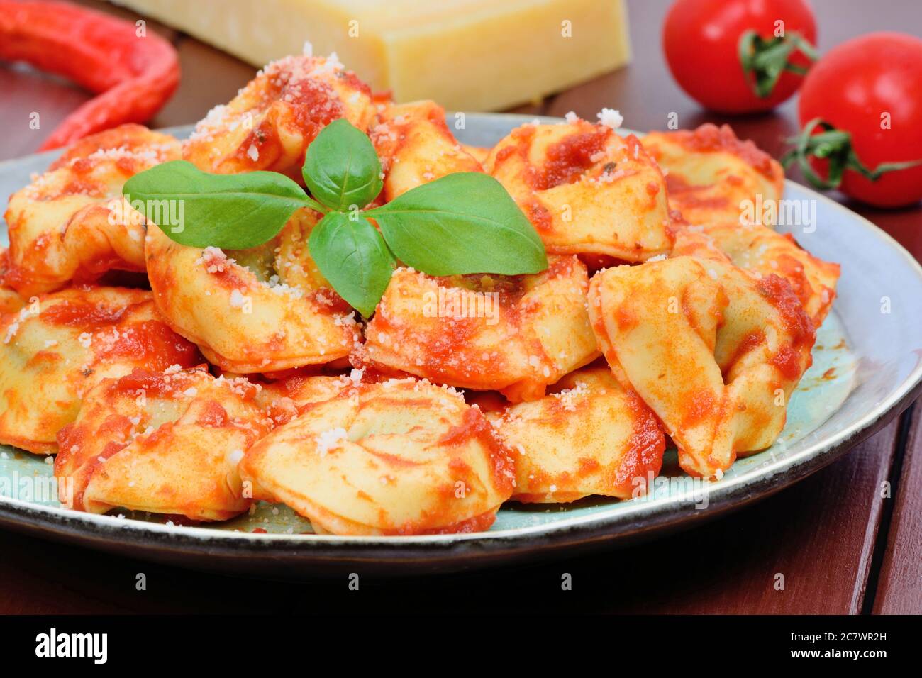 Tortellini with tomatoes sauce in a plate on wooden table Stock Photo
