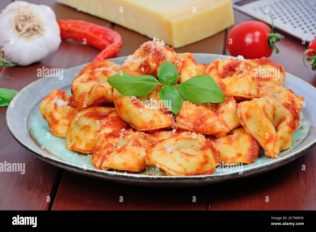 Tortellini with tomatoes sauce in a plate on brown wooden table Stock Photo