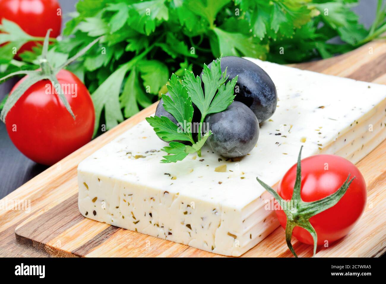 Herbs cheese with olive and cherry tomatoes on a cutting board Stock Photo