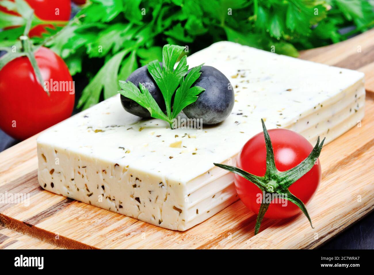 Close up of herbs cheese with olive and cherry tomatoes on a cutting board Stock Photo