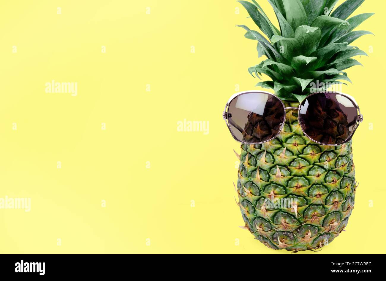 Fresh pineapple with sunglasses on yellow background Stock Photo