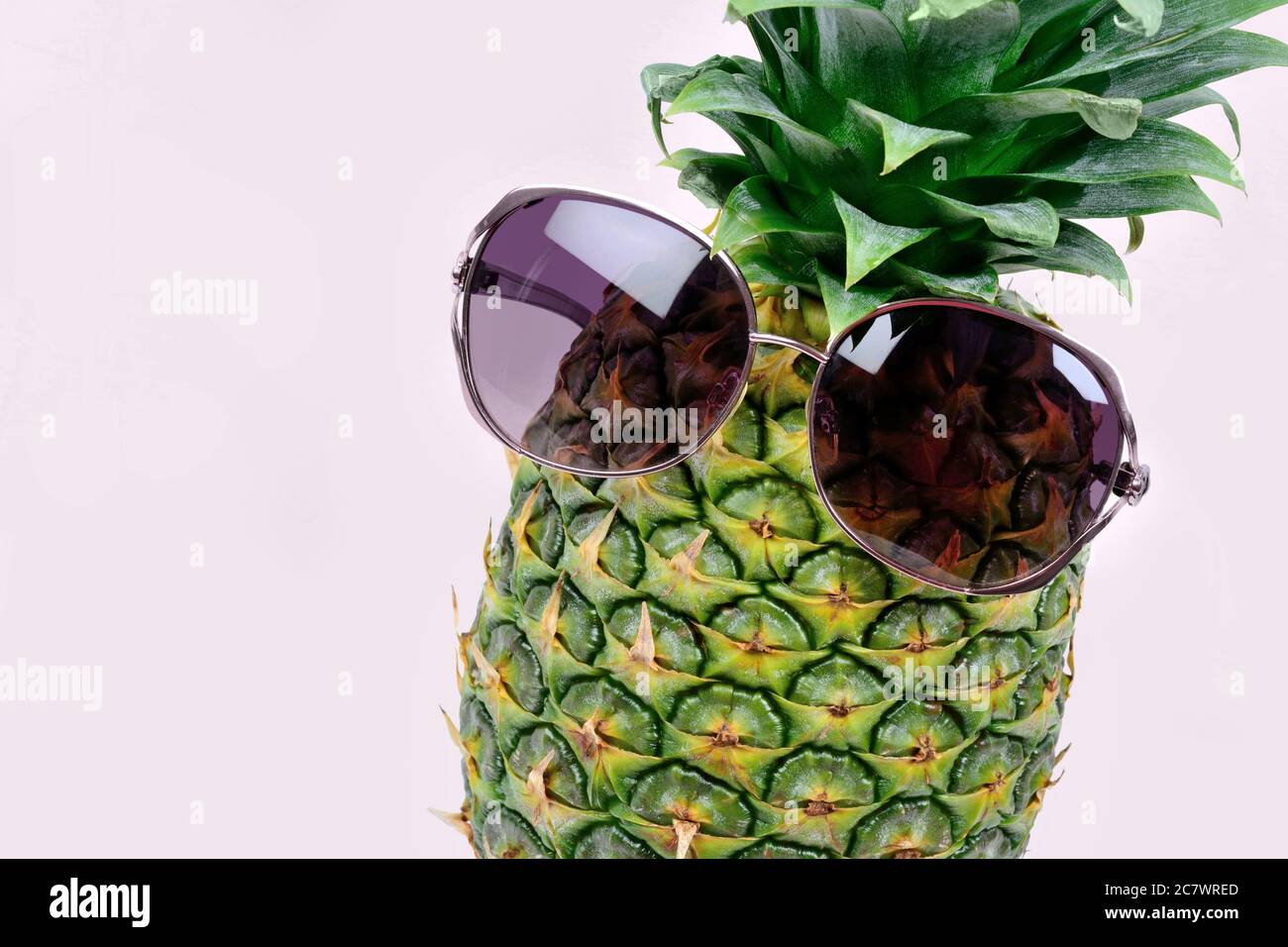 Close up of pineapple with sunglasses on violet background Stock Photo